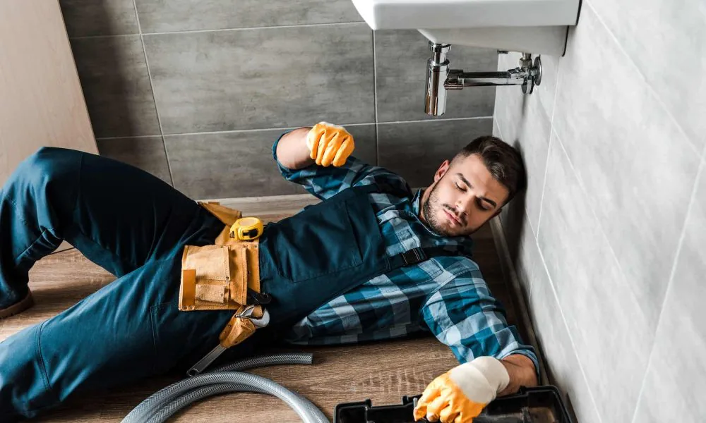 bearded-handyman-lying-on-floor-near-toolbox-in-bathroom.jpg